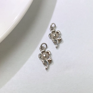 Detailed view of two silver floral charms with hanging loops for DIY jewelry making