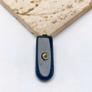 Détail d'un pendentif vintage en pierre bleue scintillante et zircon vert sur du travertin