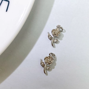 Detail view of two silver rose pendants featuring sparkling zircon flower and leaf accents