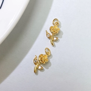 Detailed macro of golden rose flower pendants with white zircon inlay for DIY jewelry design