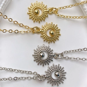 Detailed macro view of sunburst zircon pendants in gold and silver finish with chains