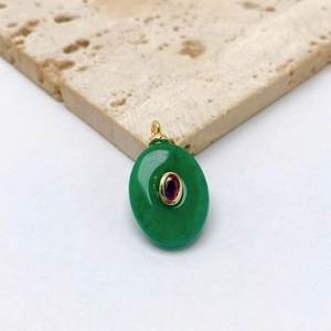 Détail d'un pendentif ovale en jade vert avec zircon rouge incrusté sur monture dorée