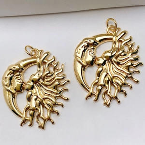 Polished gold metal pendants showing artistic sun and moon design on white background