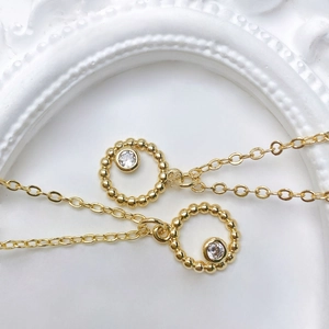 Macro shot of gold sun pendant with circular bead texture and sparkling zircon centerpiece