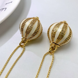 Macro view of gold spherical pendant with white enamel, ribbed gold lines and micro zircons