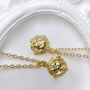 Detail of vintage sunburst coin pendant with gold plating and clear zircon accents