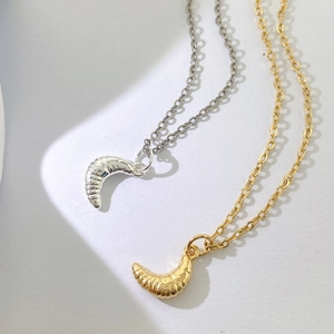 Detailansicht der croissantförmigen Anhänger in Gold und Silber mit Textur