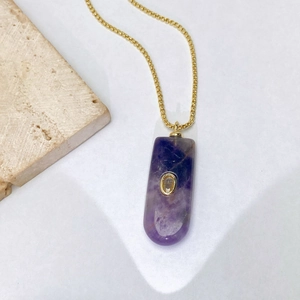 Vue détaillée du pendentif en cristal violet avec monture dorée et chaîne fine