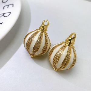 Macro detail of gold vintage spherical charms with white enamel and sparkling pave crystals
