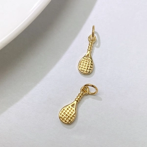 Detailed close-up of golden tennis racket pendants with hollow mesh and textured handles