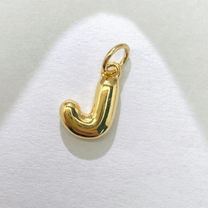 Macro de un colgante de letra J en 3D con acabado dorado pulido y detalle de asa fija