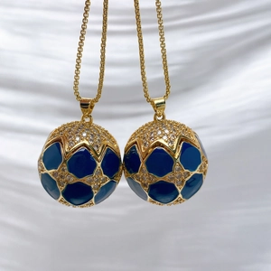 Close-up of blue enamel ball pendants with gold plating and sparkling zircon stones
