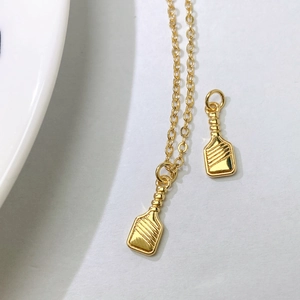 Detail of gold-plated paddle pendant necklace featuring polished metal texture and fine chain