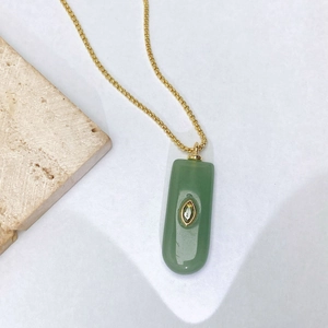 Détail d'un collier pendentif en jade vert avec chaîne dorée et zircon marquise