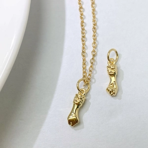 Detailed view of a gold-plated fist pendant and delicate O-chain necklace on a white background