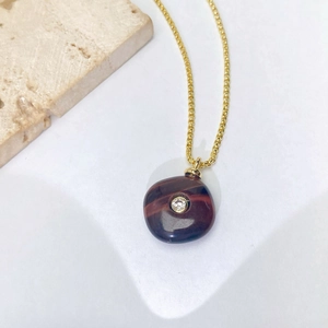 Vue détaillée d'un collier doré vintage avec pierre marron et détail en zircon