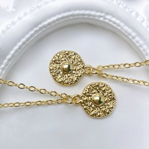 Macro view of gold sunburst pendant necklaces with detailed radial texture and orb center