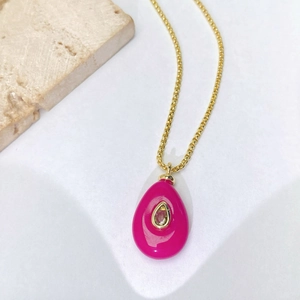 Gros plan d'un pendentif goutte d'or avec émail rose rouge et pierre de zircone fine