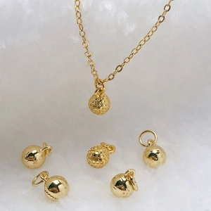 Detailed view of gold plated sphere pendants with golf ball texture on plush white background