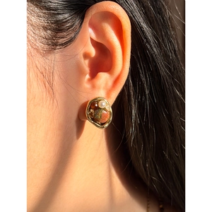 Detalle de pendientes de pata de gato con piedras naturales y marco dorado vintage