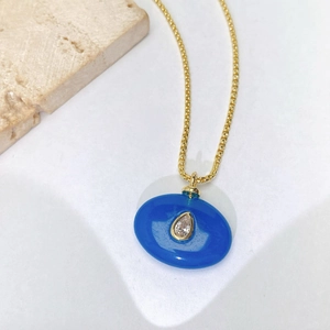 Détail d'un collier doré vintage avec pierre bleue et pendentif en zircon en forme de goutte