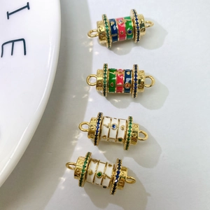 Detailed macro view of four cylindrical gold pendants with colorful enamel and zircon stones