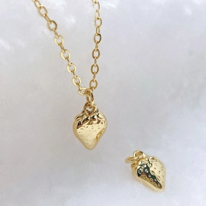 Macro shot of 3D strawberry gold pendant and O-chain necklace on soft white background