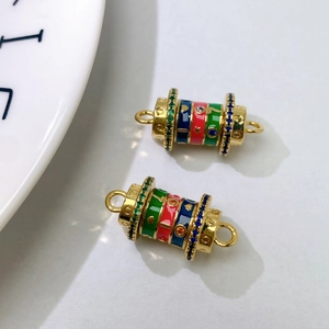 Detailed macro view of a gold-plated cylindrical charm with colorful enamel and zircon stones
