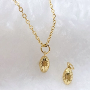 Macro shot of gold oval football-shaped pendant with textured dotted metal details