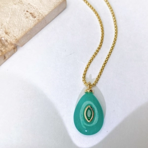 Vue macro détaillée du collier doré avec un pendentif en pierre verte en forme de goutte