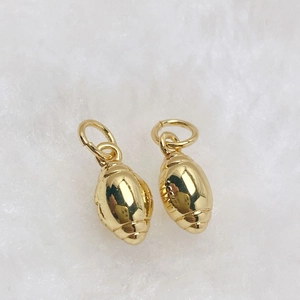 Detailed macro view of two golden football-shaped pendants with metallic stitch texture