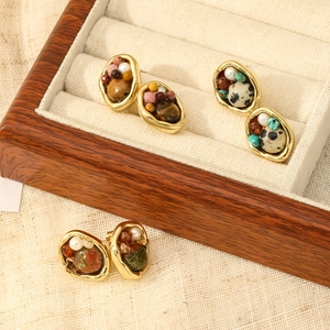 Detalle de pendientes vintage con marcos dorados e incrustaciones de piedra natural