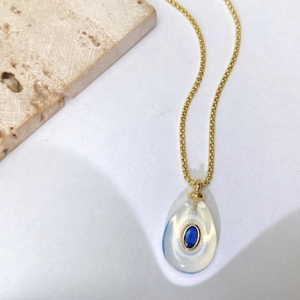 Détail d'un collier vintage avec pendentif goutte d'eau et pierre bleue sur chaîne dorée