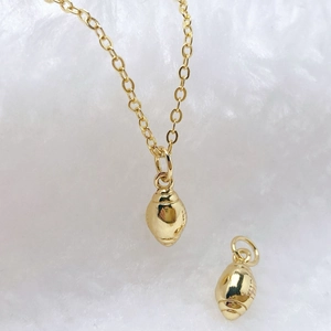 Polished gold flower pod pendant on O-chain necklace over soft white background