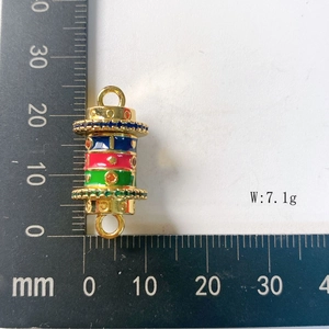 Detailed size measurement of a gold cylinder pendant with colorful enamel and crystals