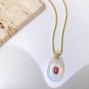 Détail d'un pendentif en opale goutte avec pierre rose sur chaîne dorée