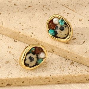 Pendientes vintage dorados con piedras naturales y perlas sobre superficie de piedra