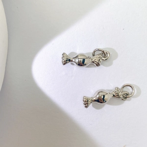 Nahaufnahme von zwei silbernen Metallanhängern in Bonbonform für DIY-Schmuck