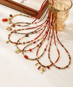 Detalle de collares de cuentas rojas con colgantes dorados de peces y caballos con luz cálida