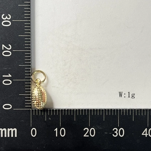 Macro shot of 1g gold football pendant with honeycomb texture and size scale