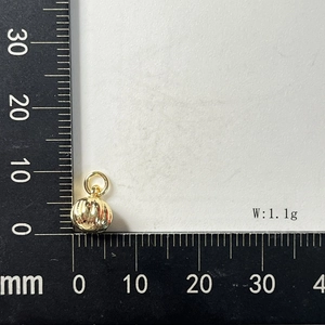 Macro shot of a 1.1g golden pumpkin stripe charm measured on a millimeter scale ruler