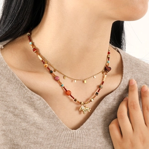 Primer plano de collares en capas con cadena dorada y cuentas de piedra de colores y caballo
