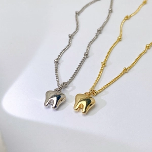 Detailansicht der gold- und silbernen Zahnanhänger Halsketten mit Kugelketten-Design