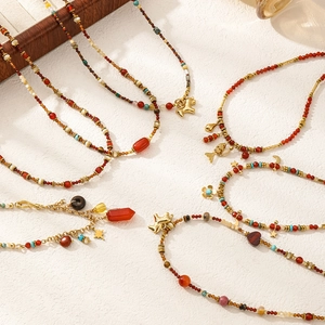Detalle de collares de perlas de ágata roja y turquesa con colgantes dorados en bandeja