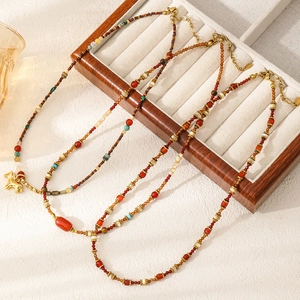Detalle de tres collares artesanales de piedra natural con colgantes de caballo rojos y oro