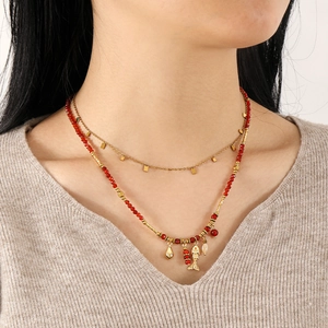 Collar de doble capa con cuentas rojas y dijes de peces mostrado sobre un modelo