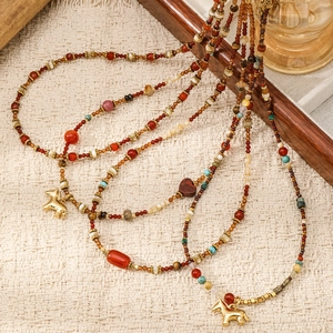 Detalle de collar bohemio de cuentas con piedras naturales rojas y colgante de caballo