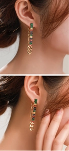 Detalle de pendientes dorados con circonitas rectangulares de colores y cadena de eslabones