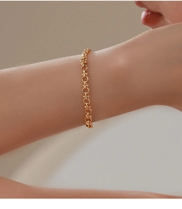 Detailansicht eines goldenen Messing-Sternarmbands am Handgelenk in minimalistischer Szene