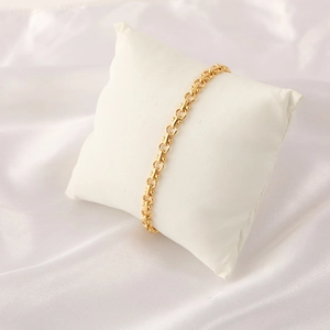 Elegantes goldenes Messing-Kettenarmband mit runden Gliedern auf weißem Seidenkissen